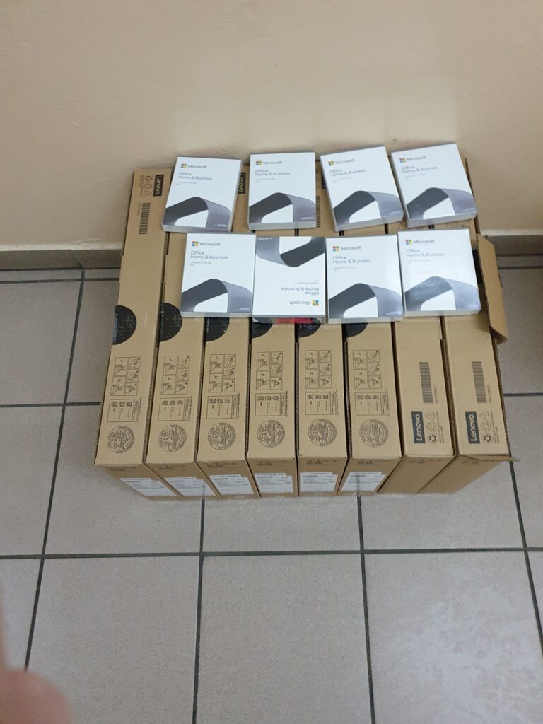 Siedem kartonowych pudełek Lenovo ułożonych obok siebie, na nich siedem białych opakowań Microsoft Office Home & Business.