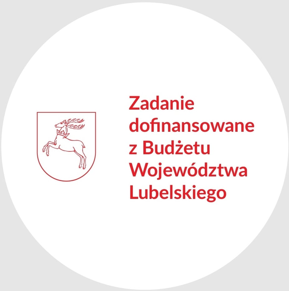 Czerwony kontur skaczącego jelenia w tarczy obok czerwonego napisu „Zadanie dofinansowane z Budżetu Województwa Lubelskiego” na białym tle.