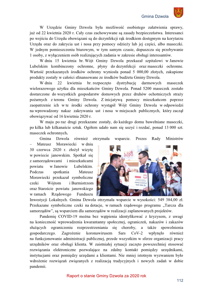 Dwóch mężczyzn w garniturach podczas wręczania symbolicznej czeku, w tle mikrofony i logo Duda 2020.