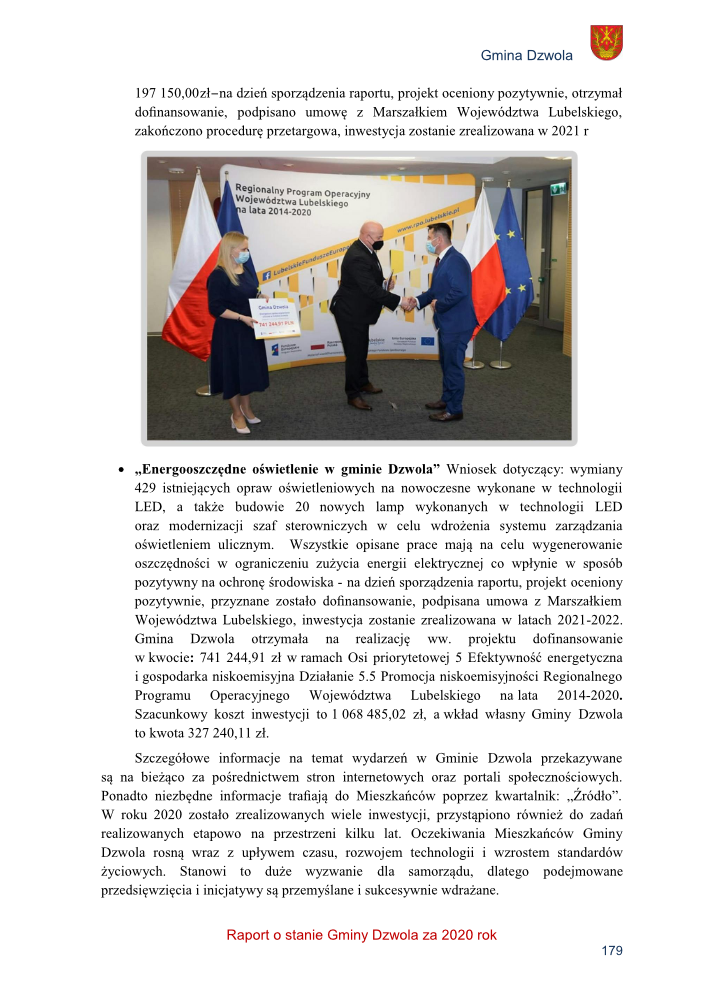 Dwóch mężczyzn w garniturach i maseczkach ściska dłonie na tle flag Polski i Unii Europejskiej oraz baneru Regionalnego Programu Operacyjnego Województwa Lubelskiego. Kobieta trzyma tablicę.