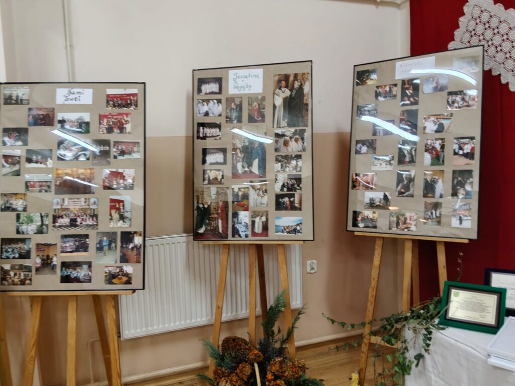 Trzy tablice na drewnianych sztalugach z wieloma małymi kolorowymi zdjęciami, podpisane: „Sami Święci”, „Jasełka i Noczyty”, „Widowiska obrzędowe”, w pomieszczeniu z beżową ścianą.